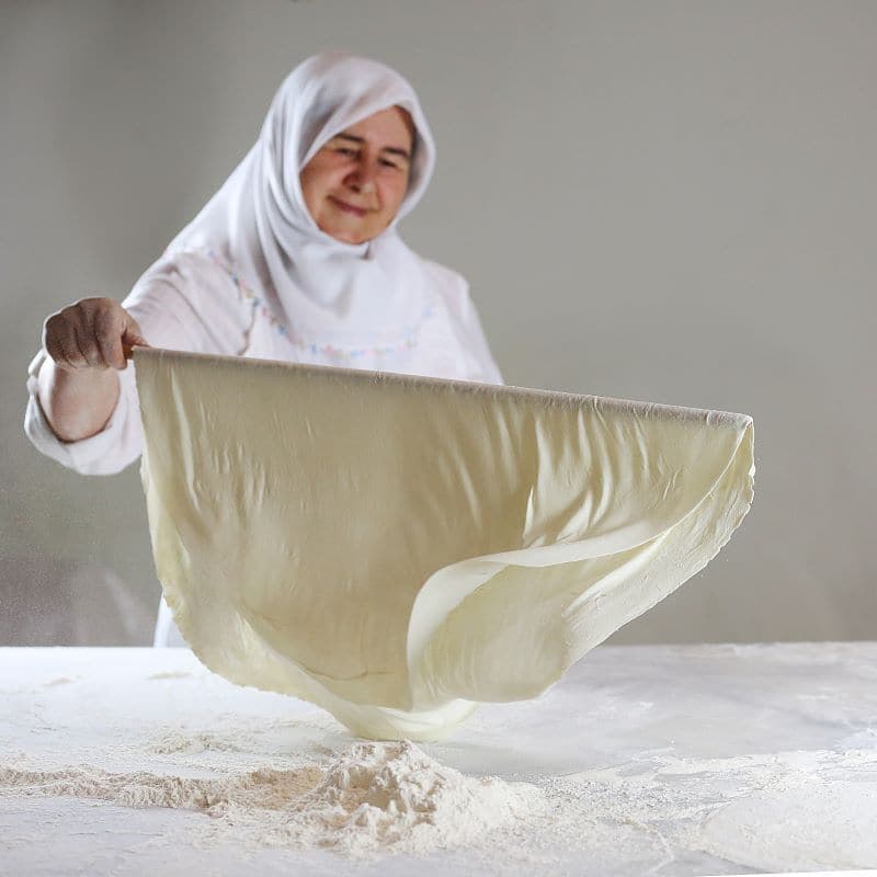 Baker stretching thin dough by hand